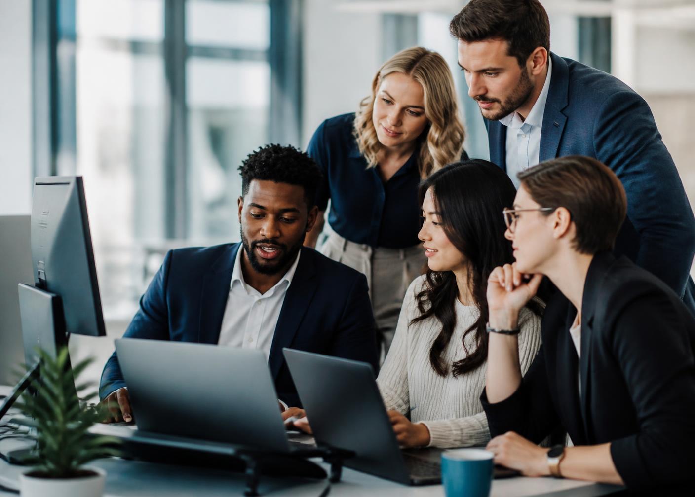 Professional team collaborating around laptops in a modern office